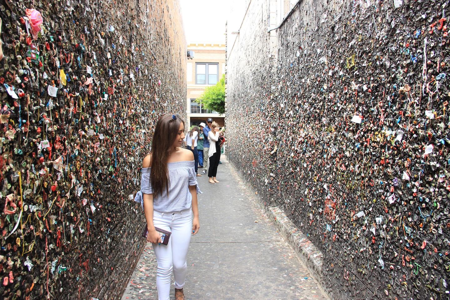 Junge Frau in einem engen hohen Gang, überall kleben bunte Kaugummis