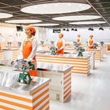 Junge Frauen mit Kopftüchern stehen an Nirostatischen in der Versuchsküche.