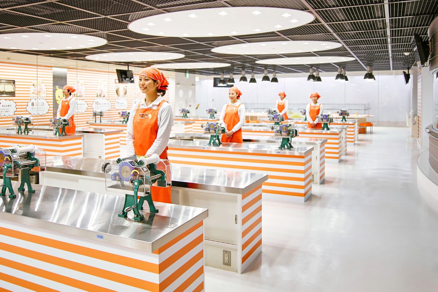 Junge Frauen mit Kopftüchern stehen an Nirostatischen in der Versuchsküche.