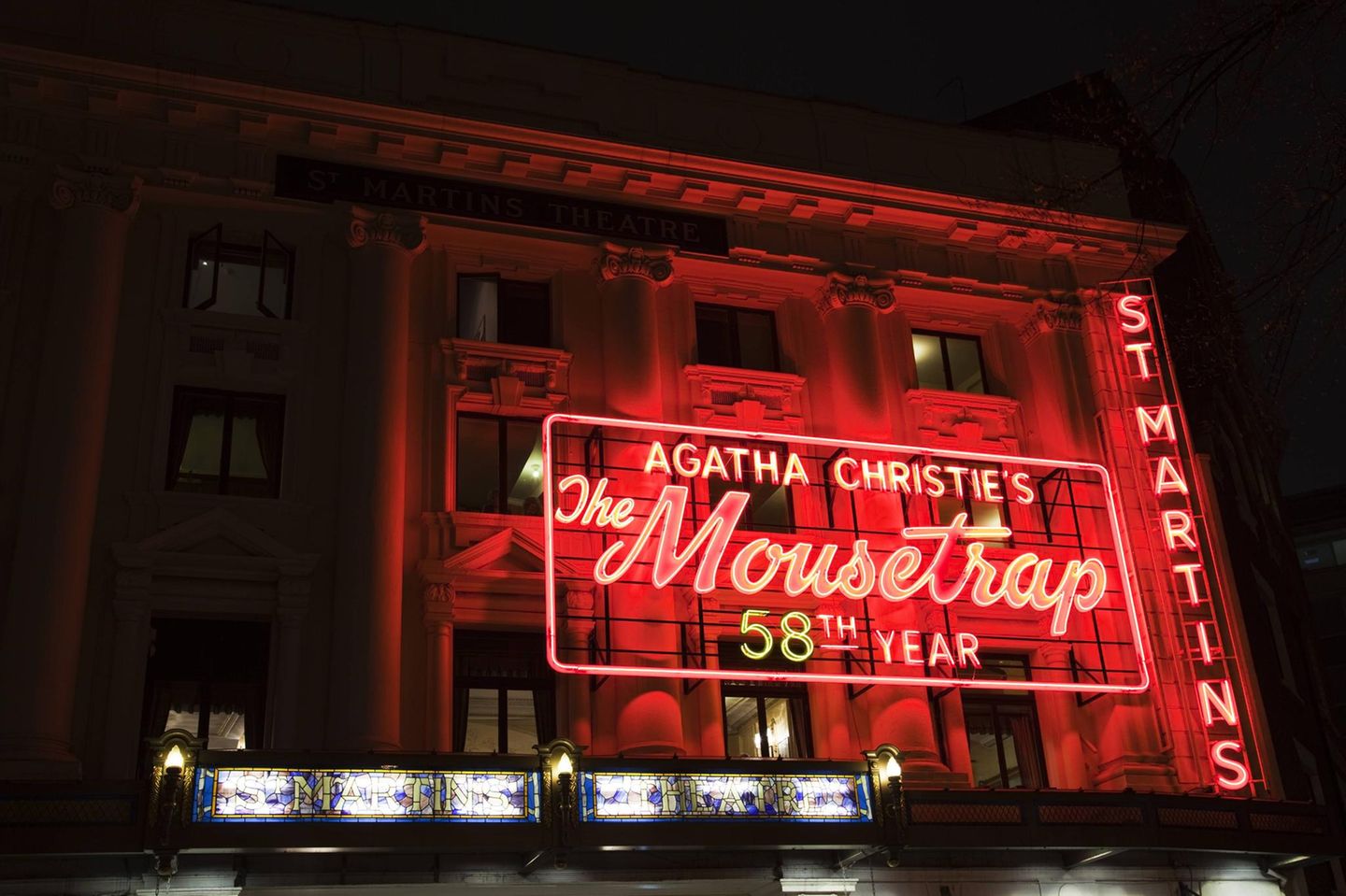 Klassizistische Theaterfassade am Abend mit großer Neonwerbung für "The Mouse Trap"