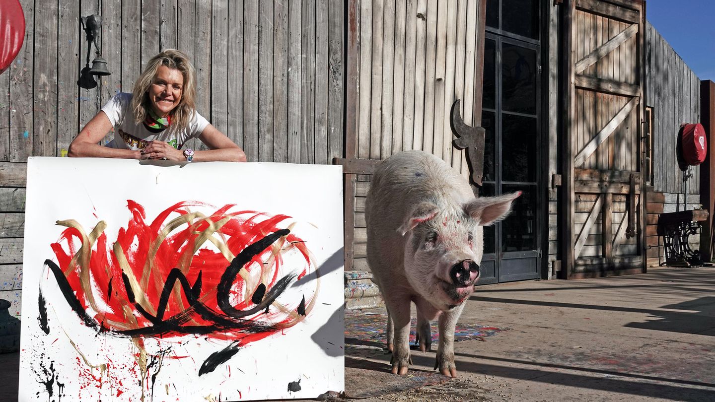 Junge Frau vor Scheunentor aus Holz, neben ihr ein großes Schwein und ein Bild.