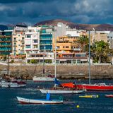 Hafenpromenade mit Häuserfront vor Bergen, davor Schiffe im Wasser