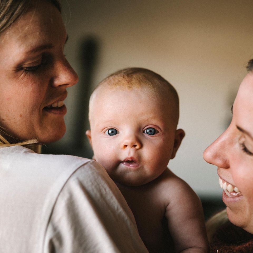 Portrait eines Babys zwischen zwei lachenden Frauen