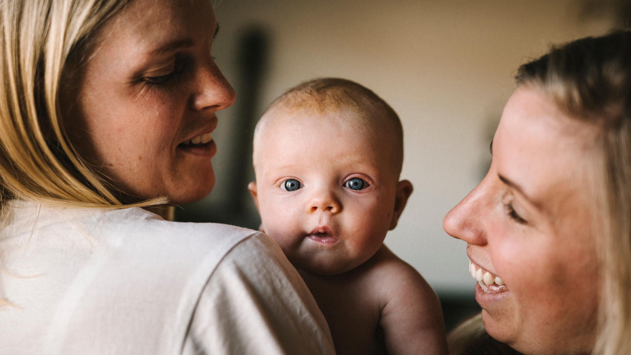 Portrait eines Babys zwischen zwei lachenden Frauen Portrait eines Babys zwischen zwei lachenden Frauen