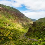 Grüne Berglandschaft mit einem Tal, durch das eine schmale Straße führt