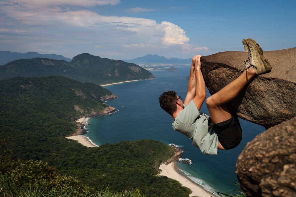 Ein Mann hängt an dem «Pedra do Telegrafo» mit dem Meer im Hintergrund. Touristen und Einheimische lassen sich hier an der Spitze des Felsens in scheinbar waghalsigen Posen ablichten.  1.5004