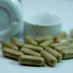 viele grüne Nahrungsergänzungskapseln liegen auf einer Fläche