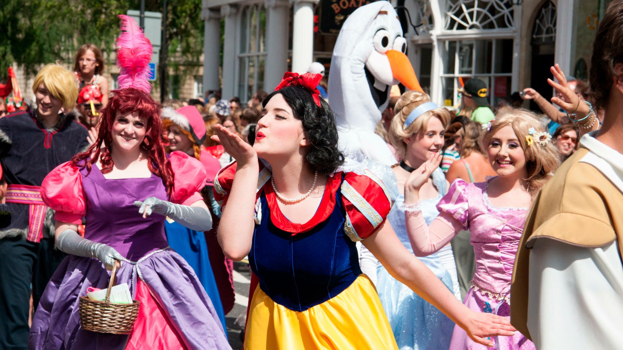 Frauen in Disney-Prinzessinnen-Kostümen, im Vordergrund Schneewittchen, die einen Luftkuss zur Seite wirft