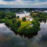 Blick auf ein weißes Schloss umgeben von Bäumen an einem Gewässer