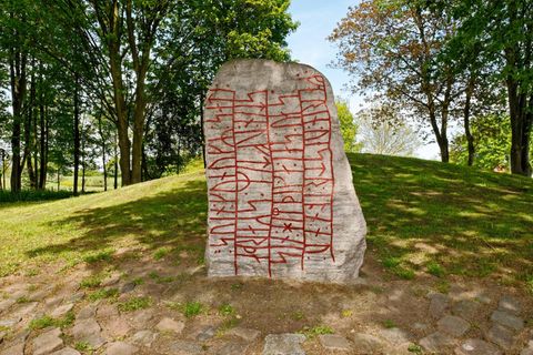 Stein umgeben von Grün, beschriftet mit roten Zeichen