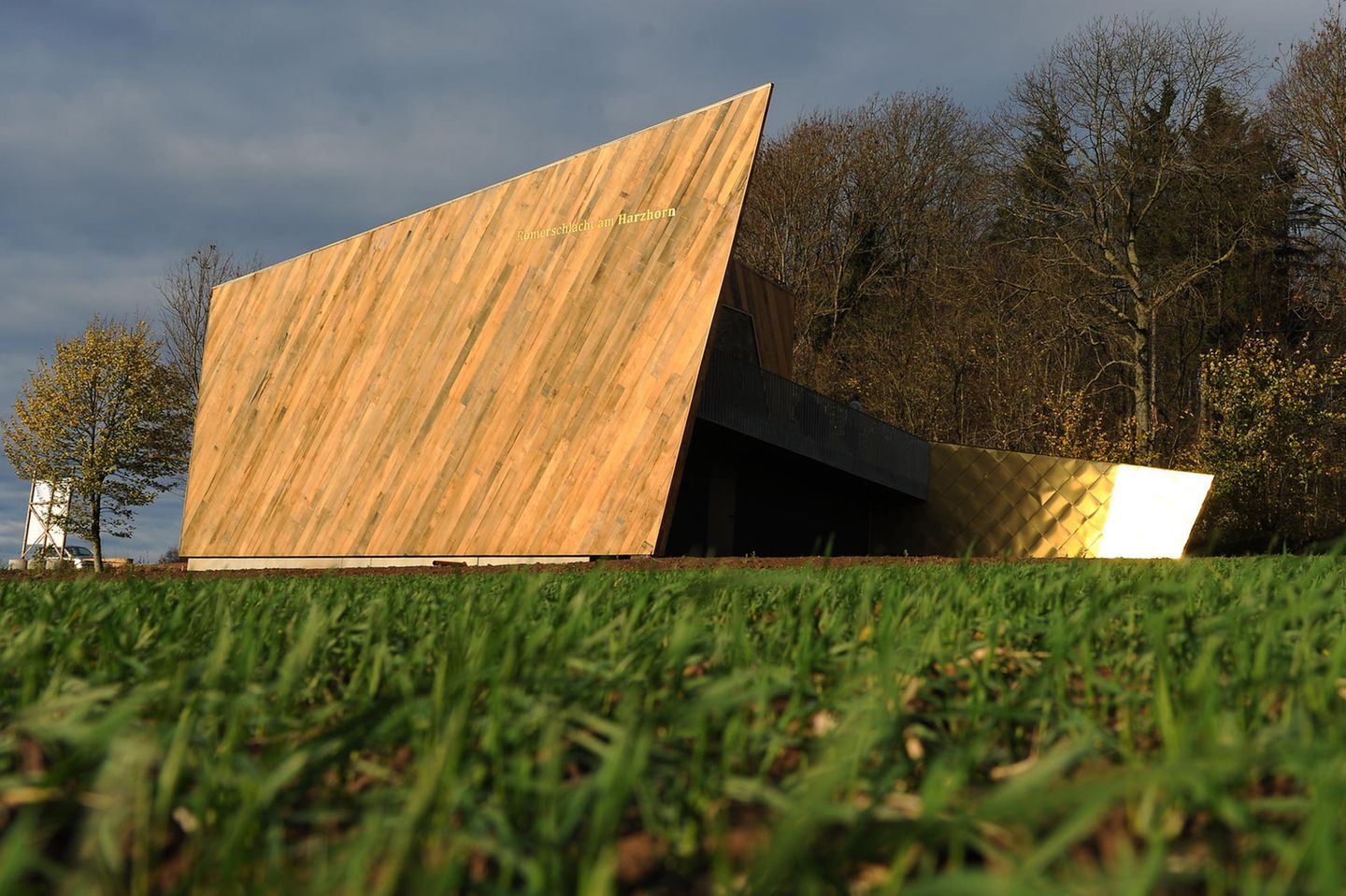 Gebäude aus Holz mit spitzer Form, dahinter Bäume