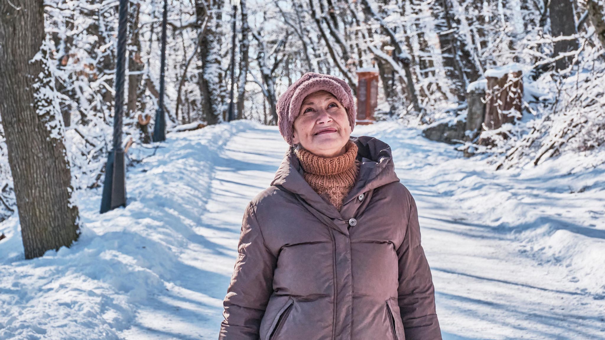 Ältere lächelnde Frau auf einem verschneiten Waldweg
