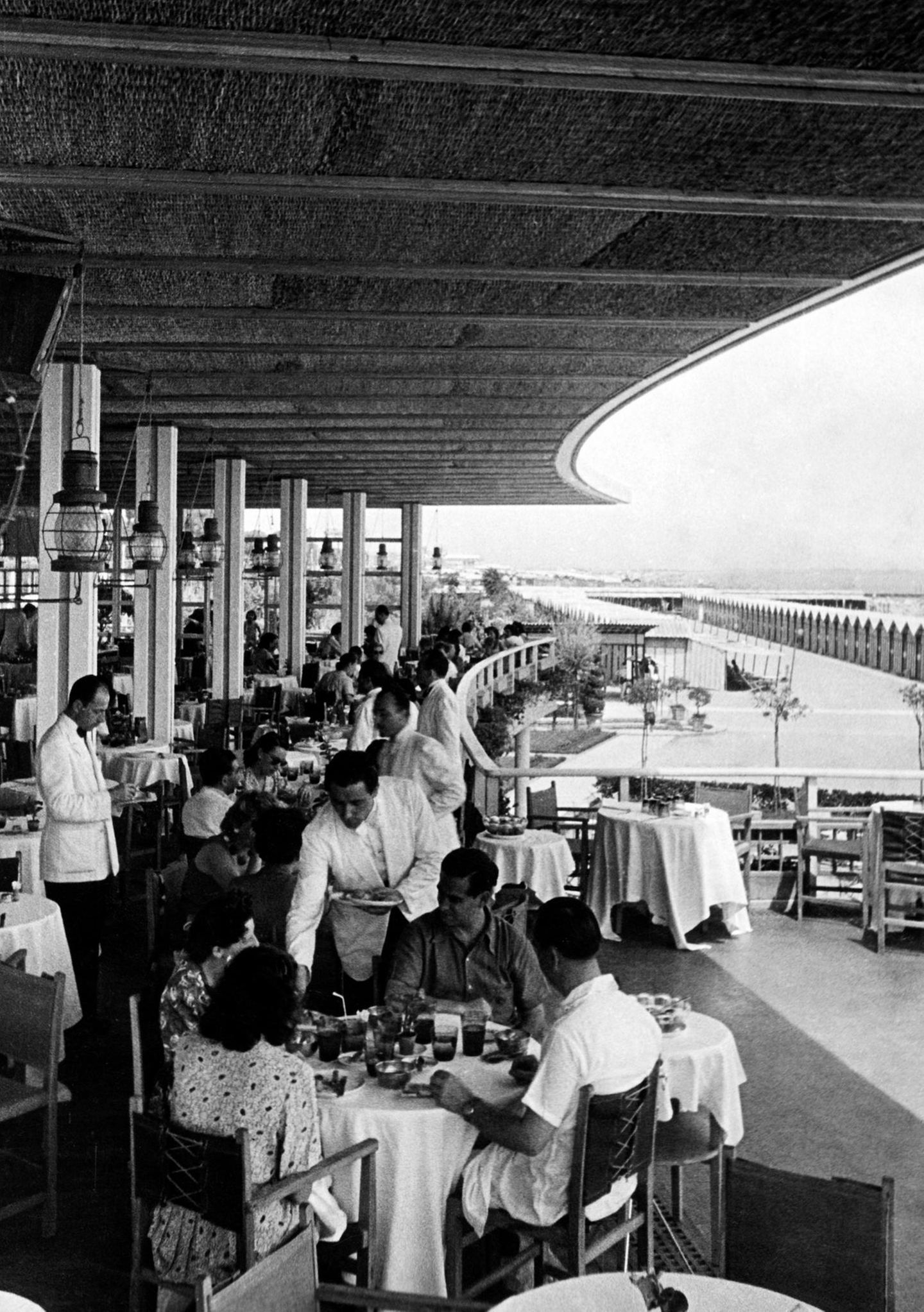 Menschen an Tischen auf einer überdachten Terrasse