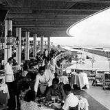 Menschen an Tischen auf einer überdachten Terrasse