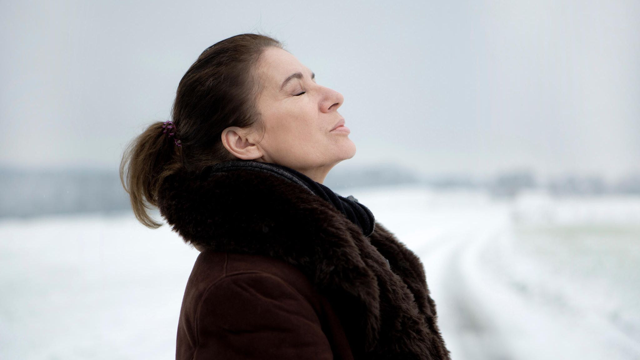 ältere Frau im Pelzmantel mit geschlossenen Augen, richtet den Kopf gen Himmel ältere Frau im Pelzmantel mit geschlossenen Augen, richtet den Kopf gen Himmel