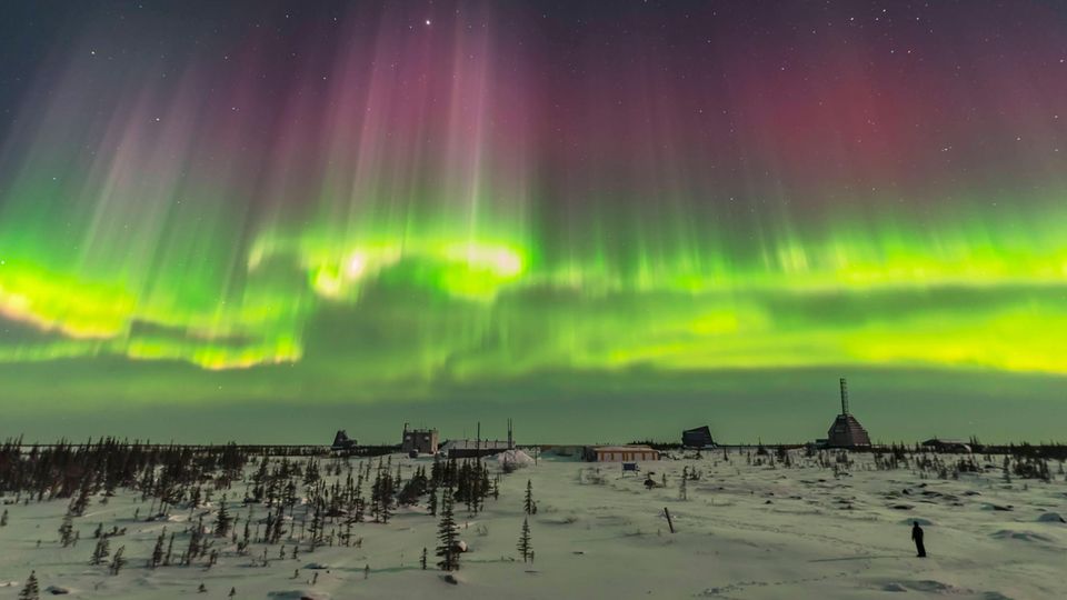 Rot-grüne Nordlichter über schneebedeckter Landschaft