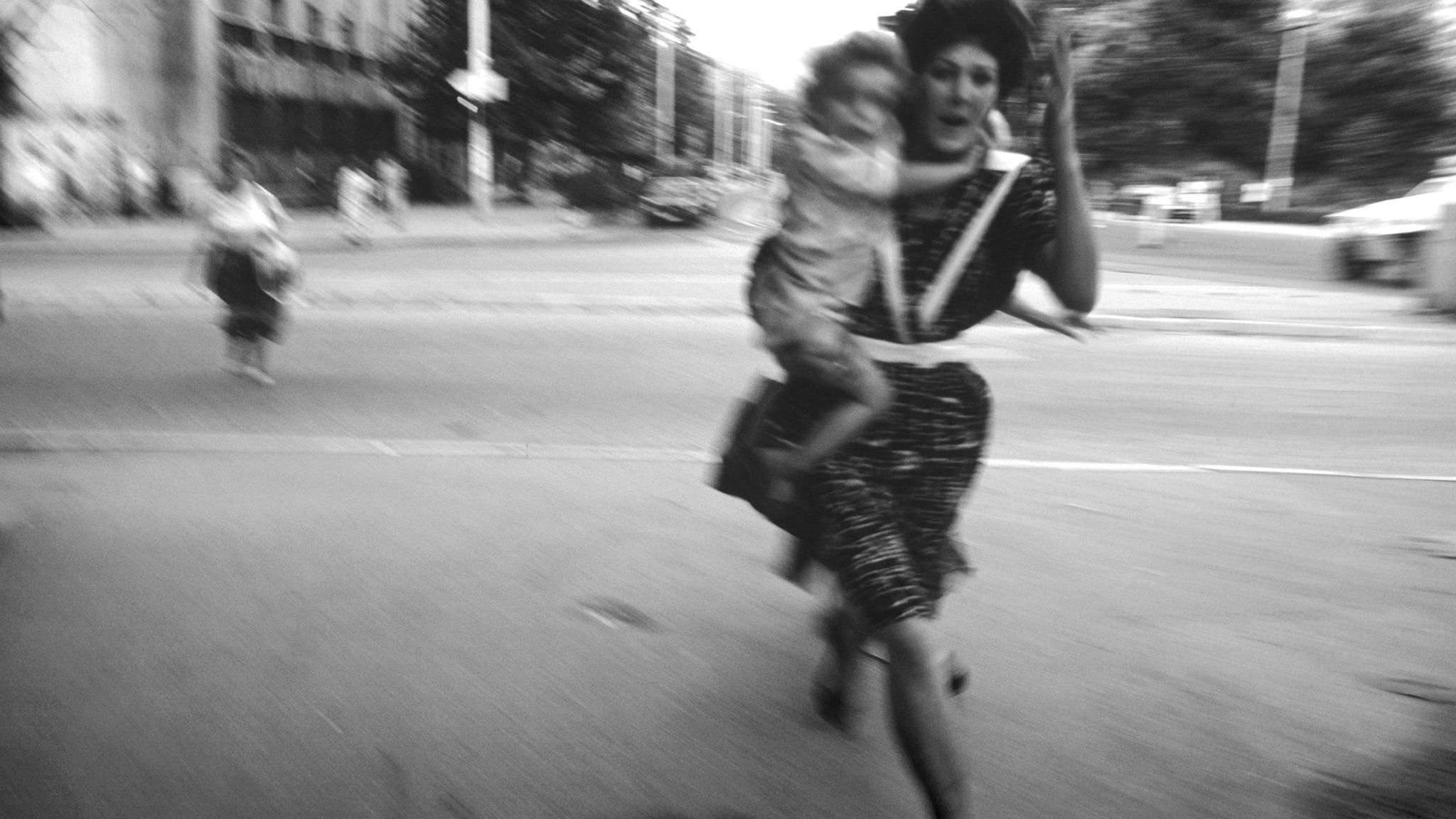 People run across an intersection to avoid sniper fire during the siege on Sarajevo by Serb troops. Around 250,000 people lost their lives in the conflict between Bosnian Muslims, Croats and Serbs that raged from 1992 to 1995 and resulted in the break-u... Eine Frau rennt mit einem Kind auf dem Arm über eine Straße