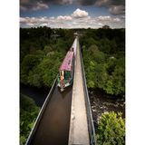 Aquädukt über Wald und Fluss, darüber fährt ein schmales Schiff