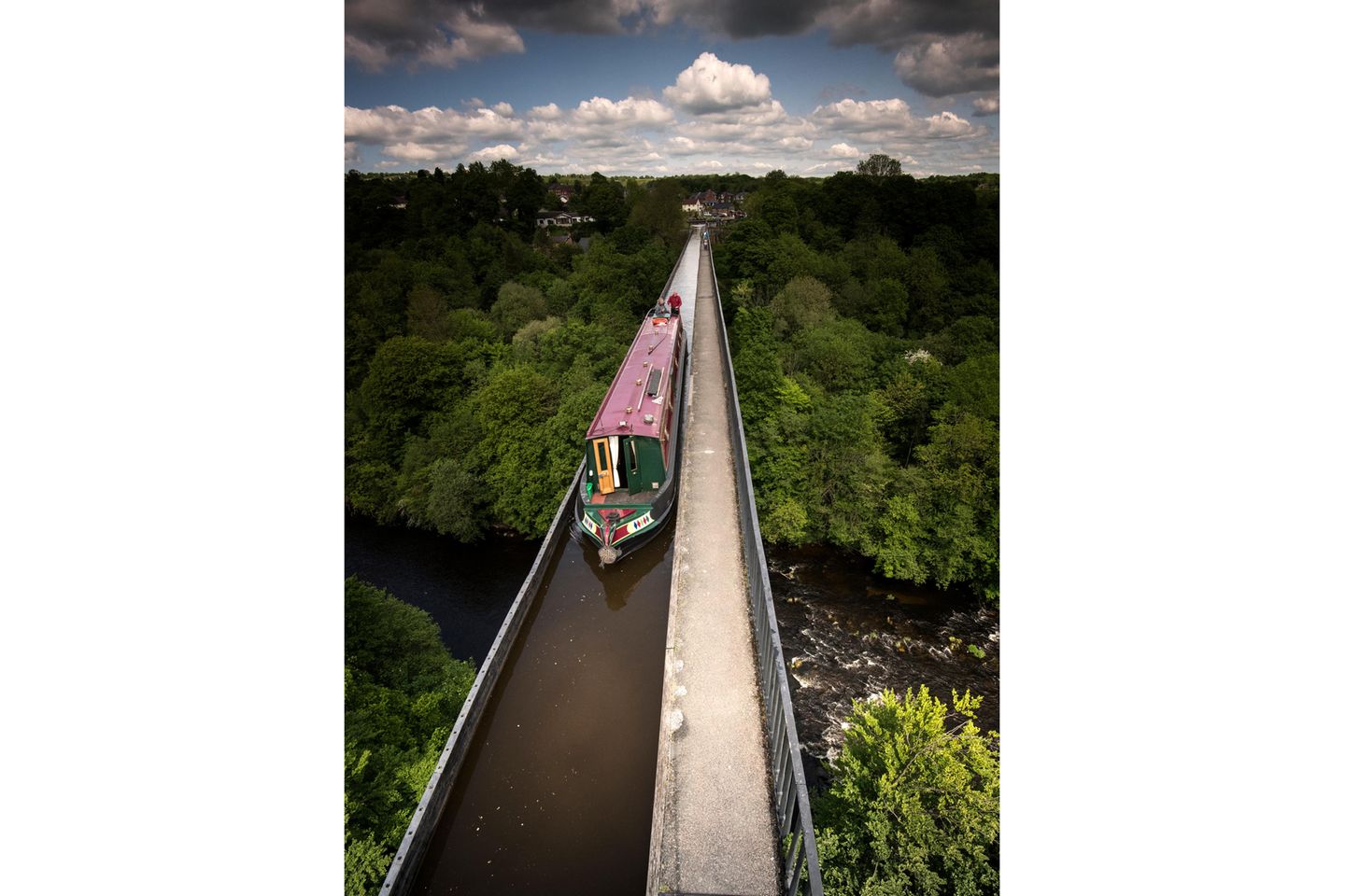 Aquädukt über Wald und Fluss, darüber fährt ein schmales Schiff