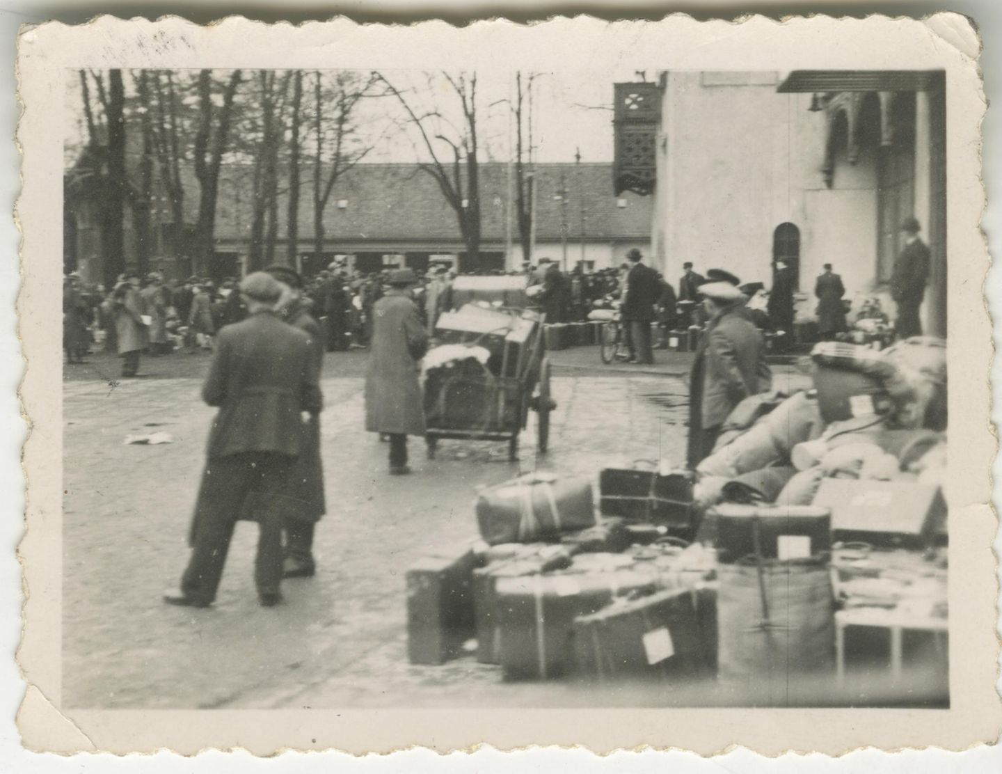 Habseligkeiten, in Koffer verpackt Menschenmenge im Hintergrund, davor vereinzelt Menschen und viele Koffer