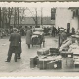 Menschenmenge im Hintergrund, davor vereinzelt Menschen und viele Koffer