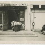 Person zieht einen großen, vollbeladenen Container in ein Gebäude