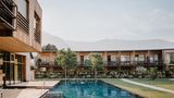 Pool umgeben von Hotelbau aus Holz, ein paar Büsche und zwei Bäume davor