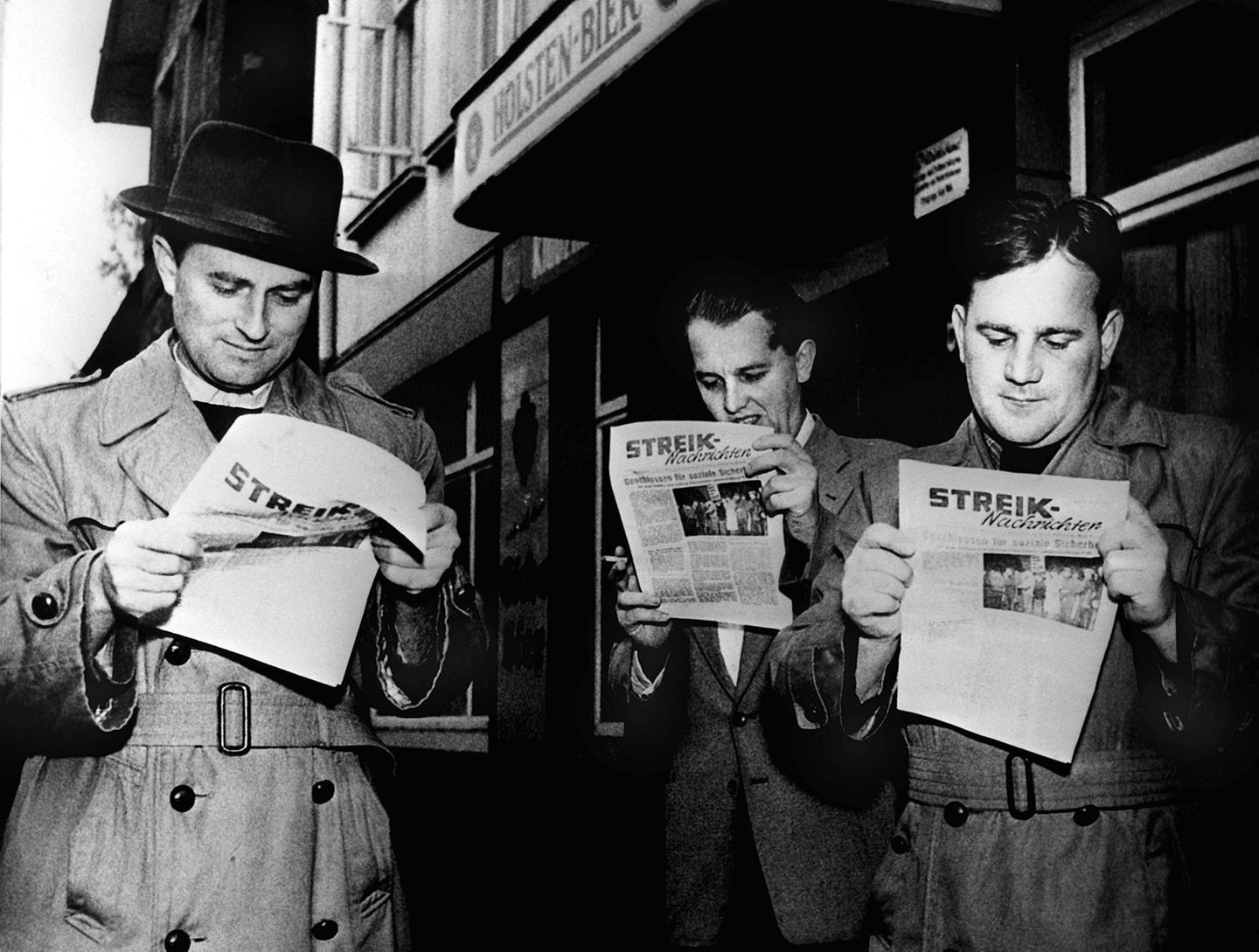 Lohn auch im Krankheitsfall Männer lesen eine Streikzeitung