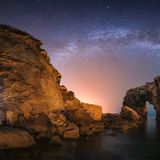 Felslandschaft und Meer mit Milchstraße und Sternenhimmel bei Nacht