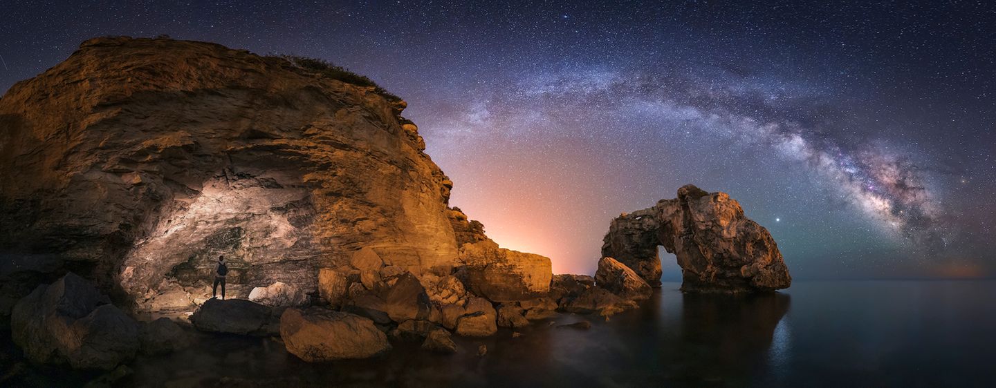 Felslandschaft und Meer mit Milchstraße und Sternenhimmel bei Nacht