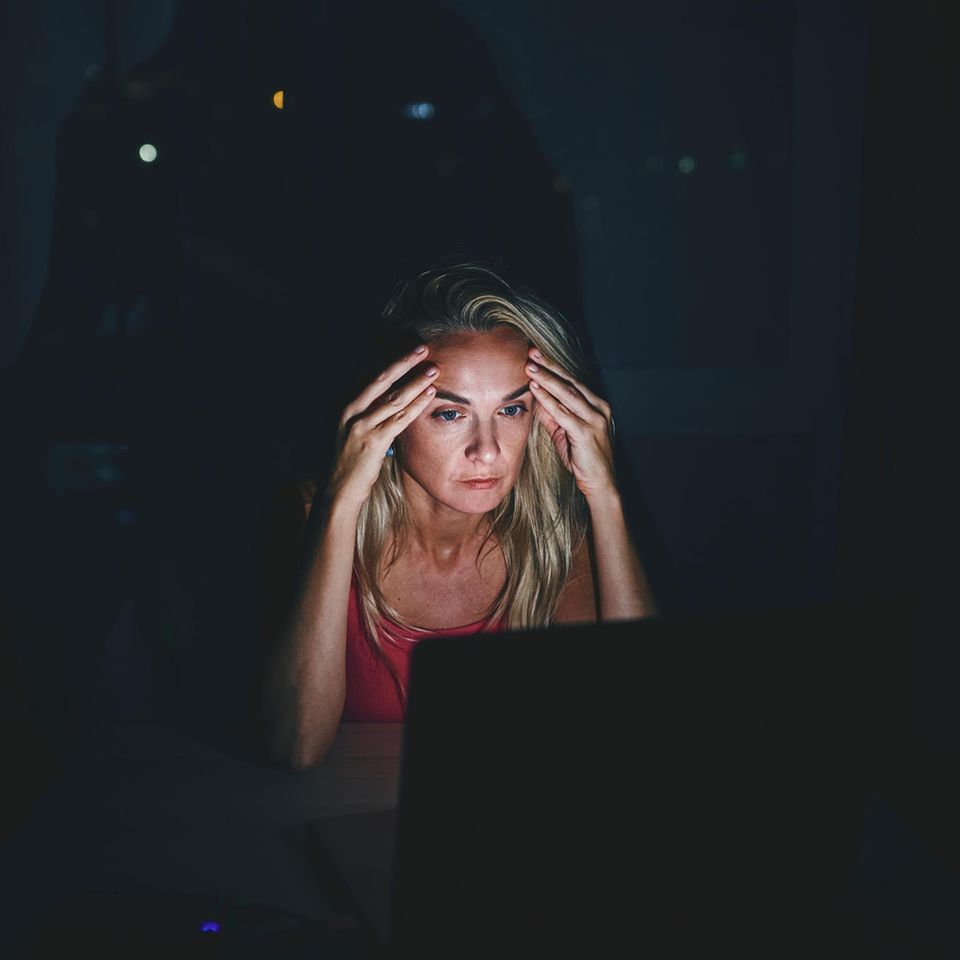 Eine Frau schaut sorgenvoll auf ihren Laptop-Bilschirm