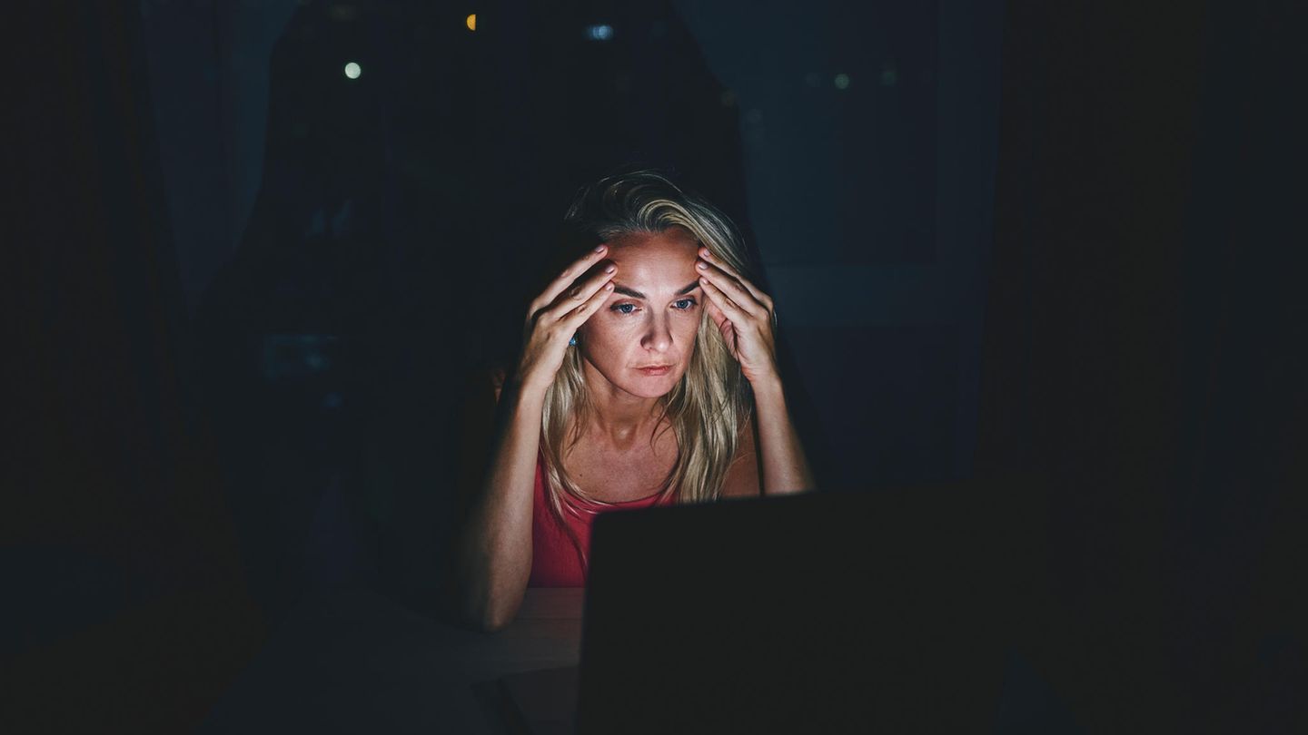 Eine Frau schaut sorgenvoll auf ihren Laptop-Bilschirm