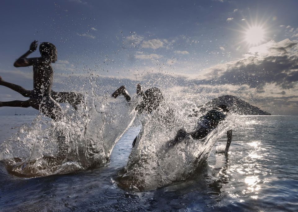 Vier Kinder springen in den See, Wasser spritzt Abendstimmung