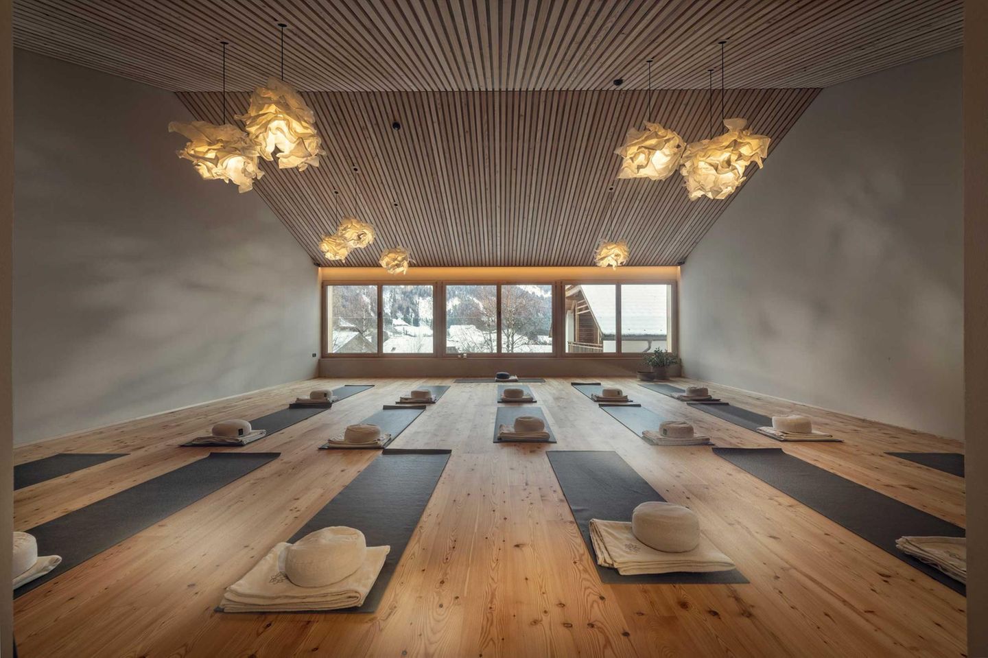 Yogaraum mit Matten und Kissen, Blick nach draußendurch Fensterfront