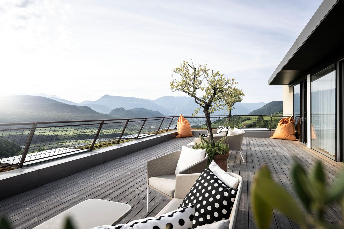 Dachterrasse mit Sitzmöbeln und Blick über grüne Berglandschaft