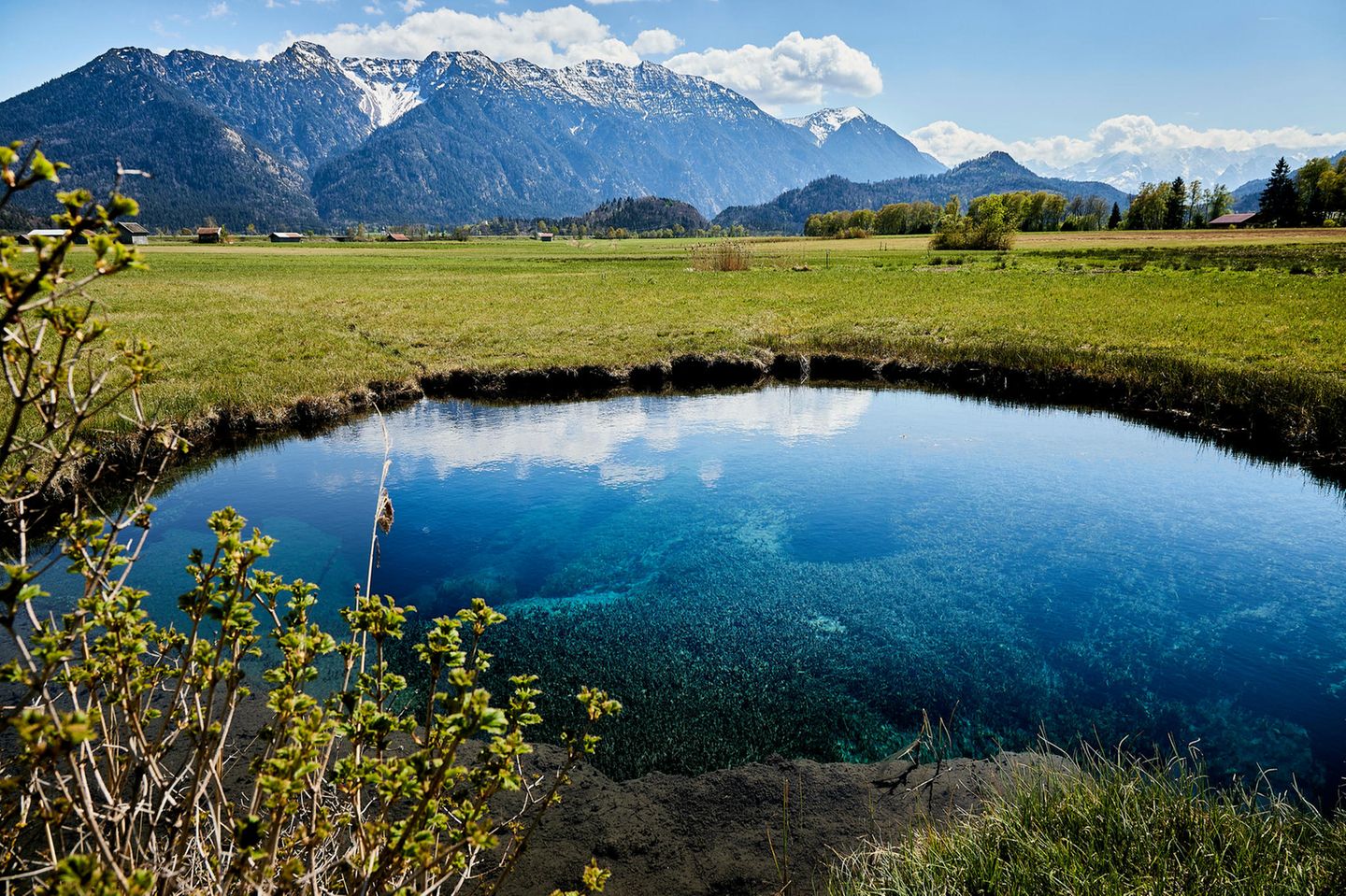 Teich umgeben von Wiese mit Berglandschaft im Hintergrund