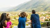 Eltern mit Kindern genießen Ausblick auf ein Dorf im Tal