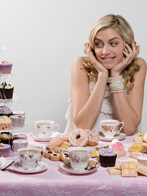 Frau an einem Tisch, umgeben von Cupcakes und anderen Desserts