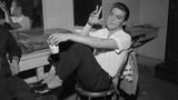Elvis Presley sitzt 1956 in einem Backstage-Raum auf einem Stuhl und raucht