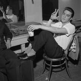 Elvis Presley sitzt 1956 in einem Backstage-Raum auf einem Stuhl und raucht