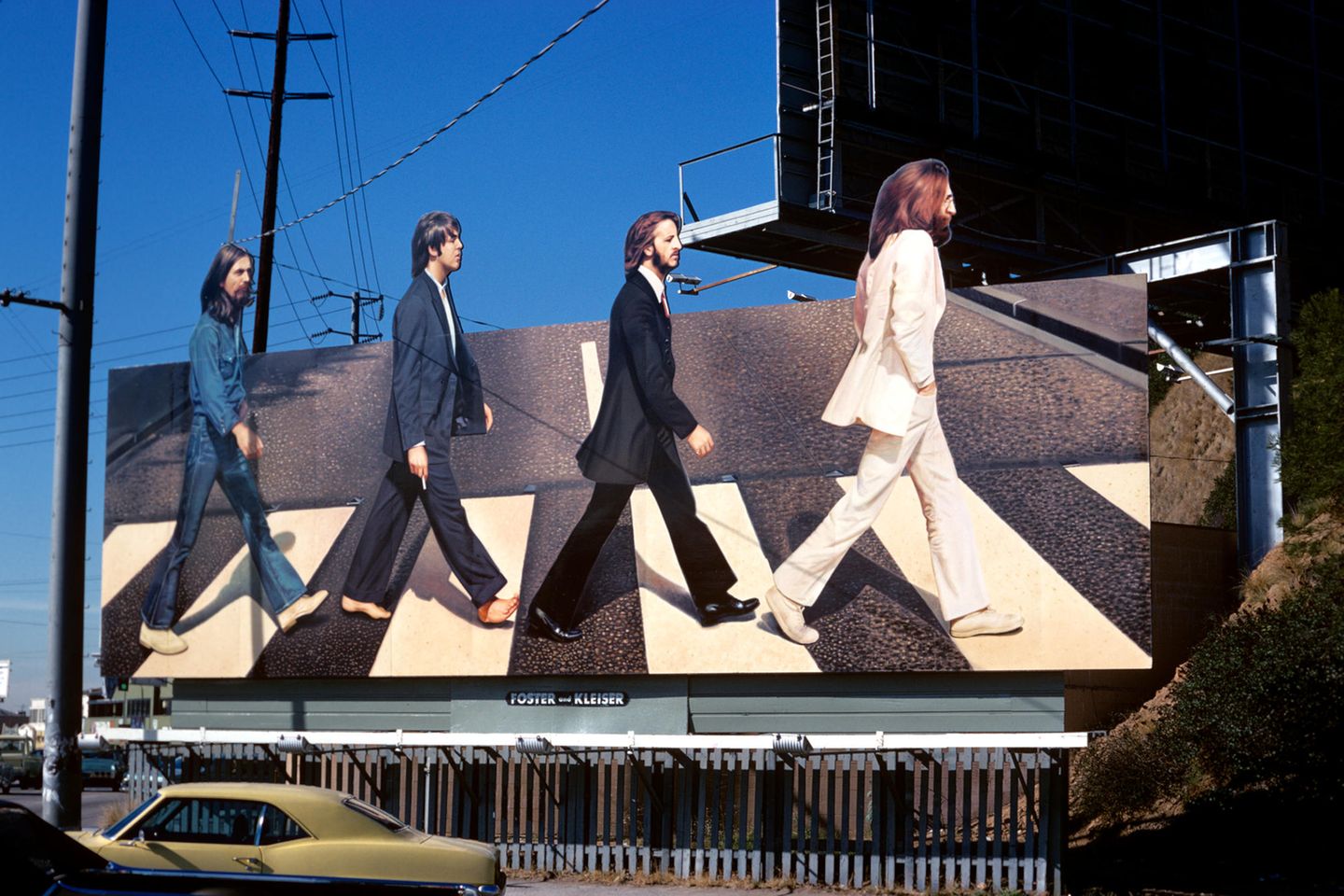 Eine Werbetafel zeigt die Beatles, wie sie hintereinander einen Zebrastreife überqueren