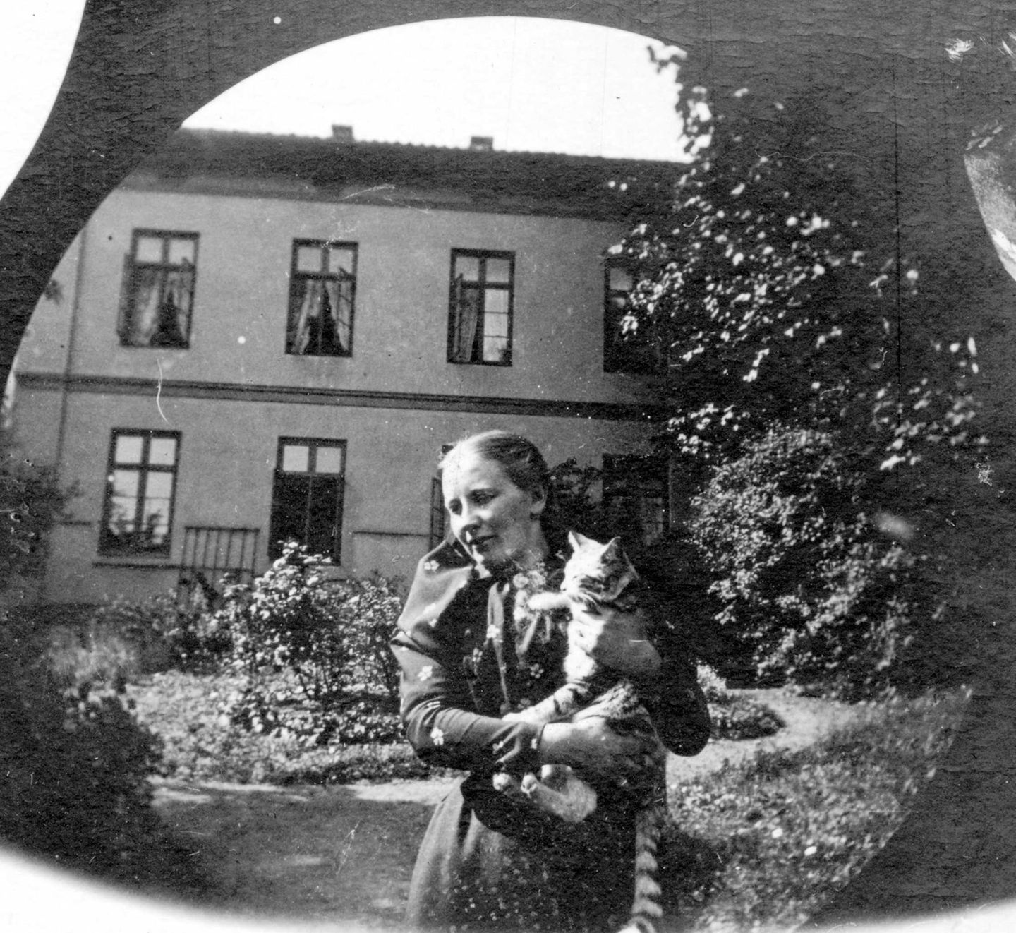 Die Größe der kleinen Momente Eine Frau steht in einem Garten und trägt eine Katze auf dem Arm