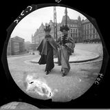 Zwei Frauen überqueren eine Straße, im Hintergrund steht ein repräsentatives Gebäude