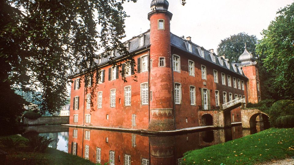 Rotes Gebäude umgeben von einer Art Burggraben, links ein Baum Rotes Gebäude umgeben von einer Art Burggraben, links ein Baum