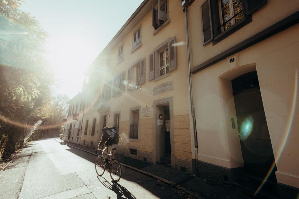 Straßenansicht im Gegenlicht mit vorbeifahrendem Radler