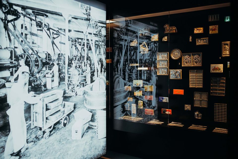Historienaufnahme der Schokoladenherstellung sowie historische Schokoladenformen hinter einer Vitrine