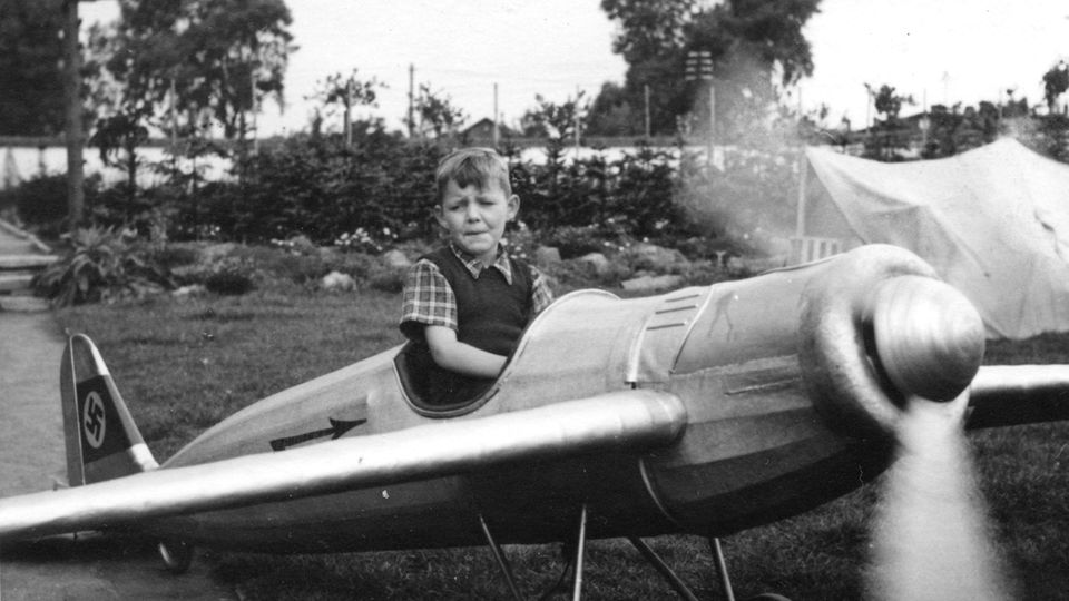 Ein kleiner Junge in einer Spiel-Propellermaschine mit Hakenkreuz-Symbol Ein kleiner Junge in einer Spiel-Propellermaschine mit Hakenkreuz-Symbol