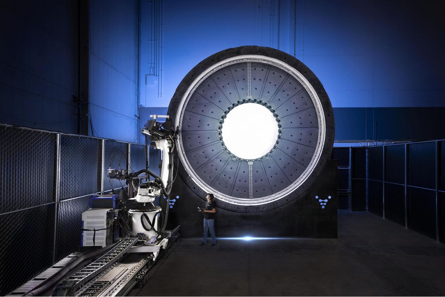 Runde, leuchtende Technik, daneben Geräte und ein Mensch der daneben sehr klein aussieht