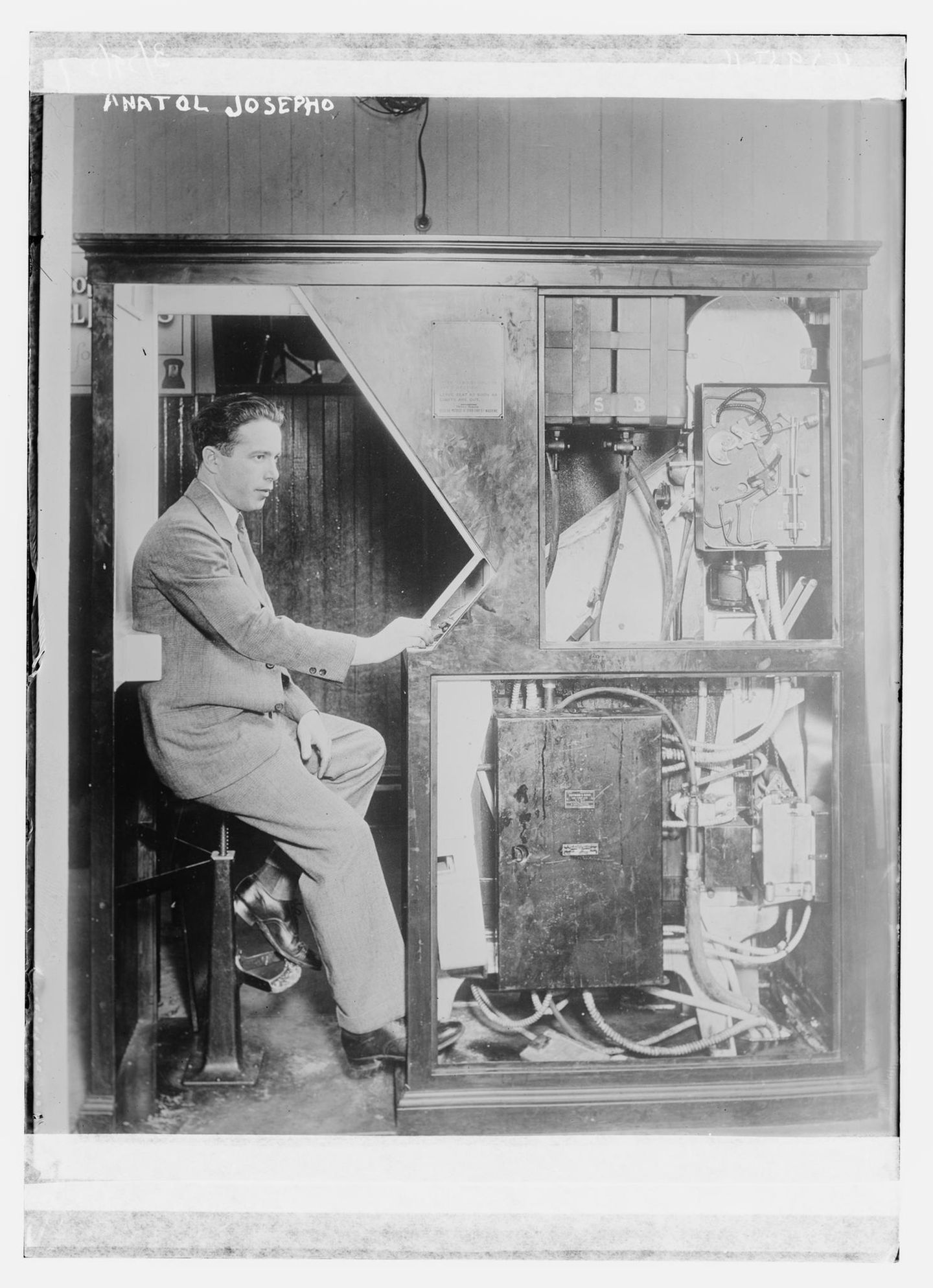 Mann in Anzug sitzt in einer altmodischen Fotokabine