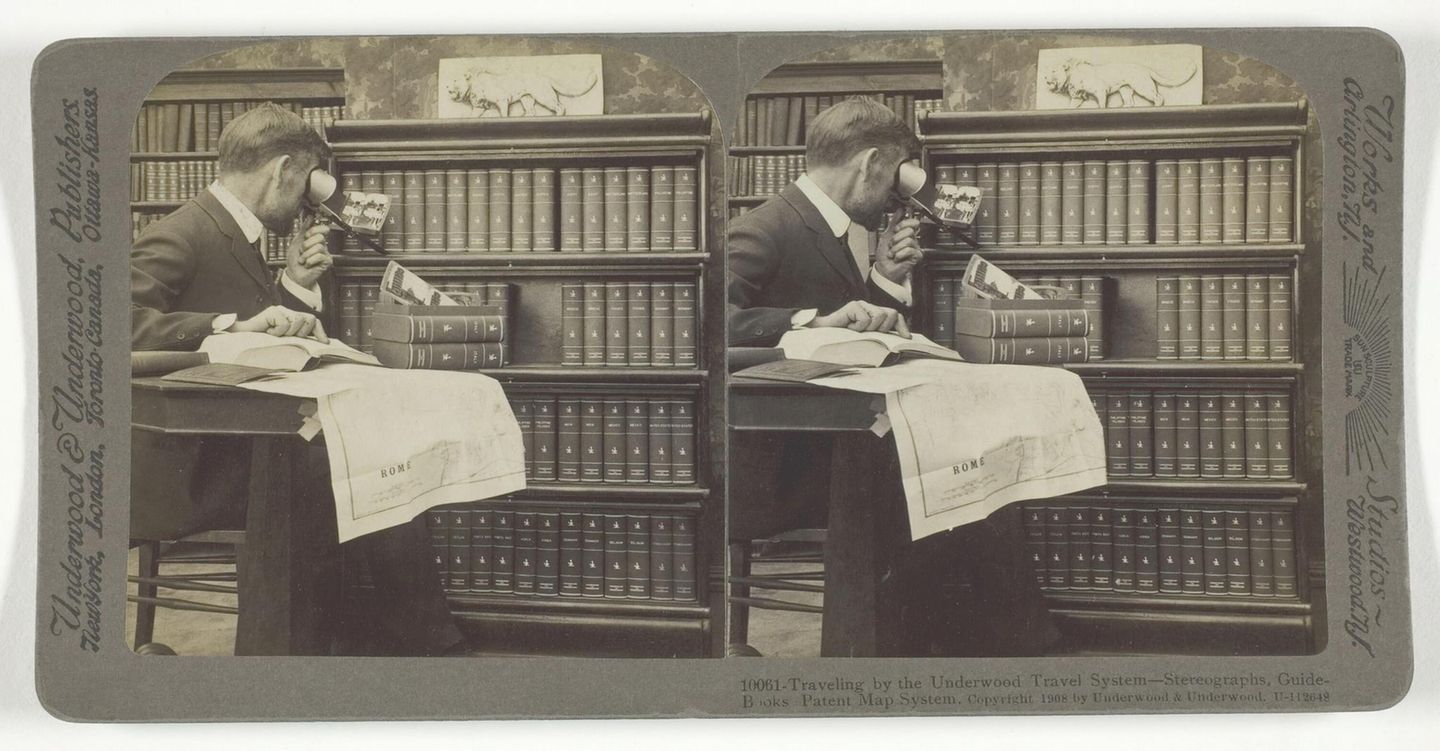 Eine Kamera mit zwei Augen: Die Stereoskopie verleiht Tiefe Mann schaut vor einem Bücherregal durch ein fernglasartiges Objekt, auf dem Schoß eine Weltkarte
